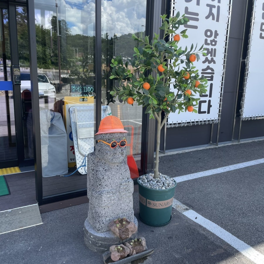 모자와 선글라스를 쓴 돌하르방과 감귤나무 화분. 제주도 감성을 살린 포토존입니다.
