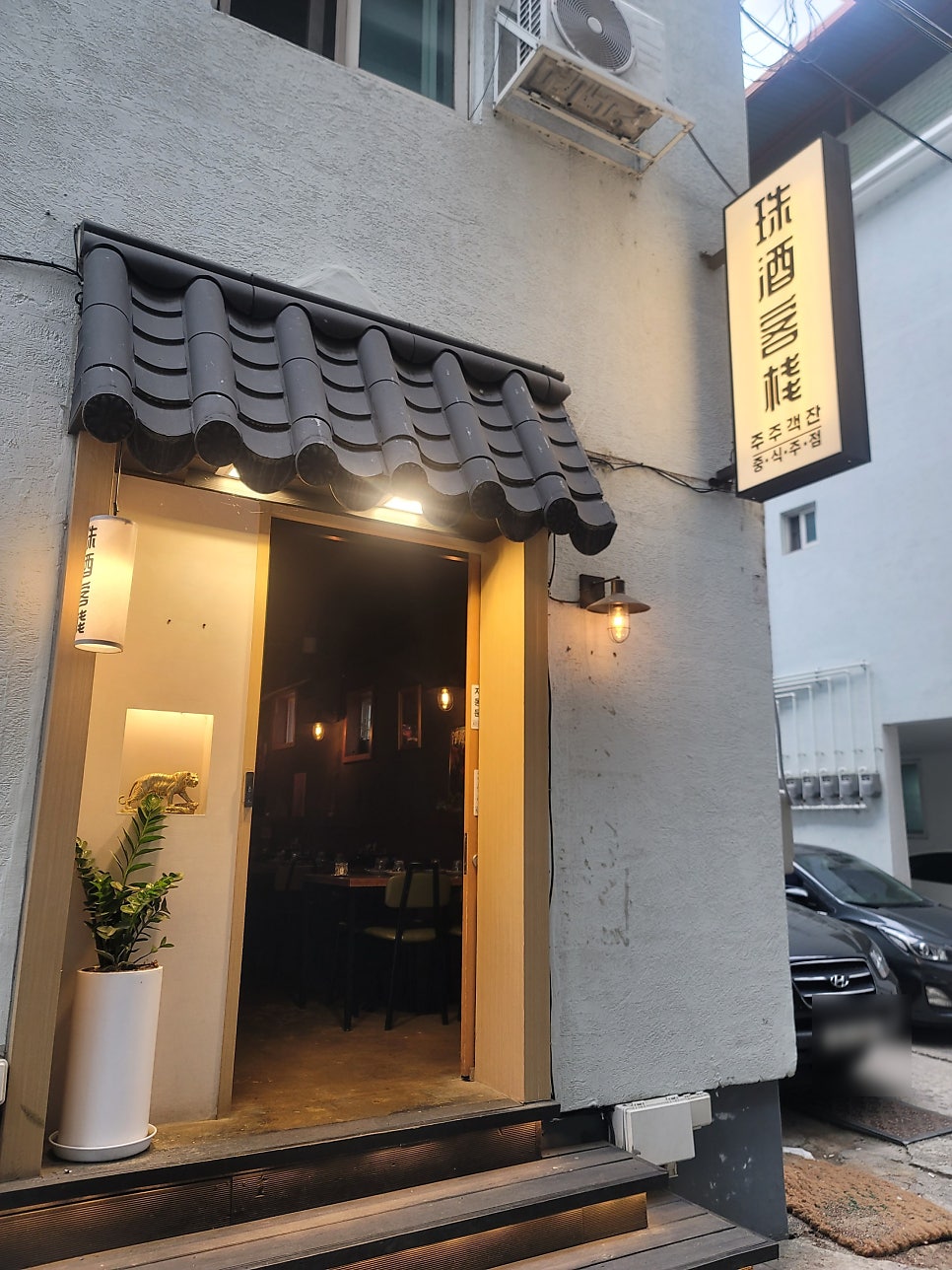 남춘천역 근처의 감성 있는 주주객잔 입구. 동백꽃 감성의 간판과 따뜻한 조명이 특징입니다.