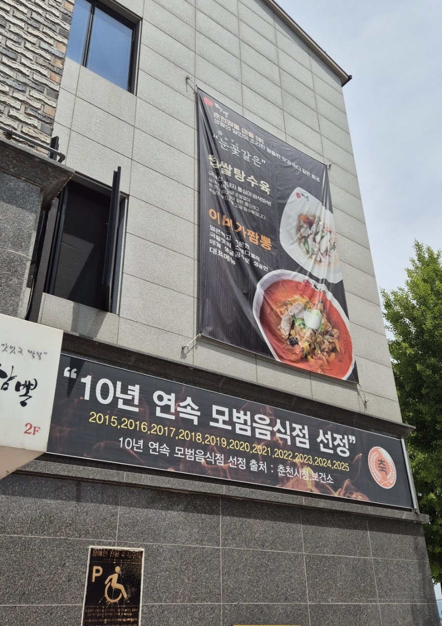 이비가짬뽕 춘천점 건물 외부. 건물 규모가 크고 간판에 한우 짬뽕과 한우 짜장, 로봇배달 안내가 명확합니다.