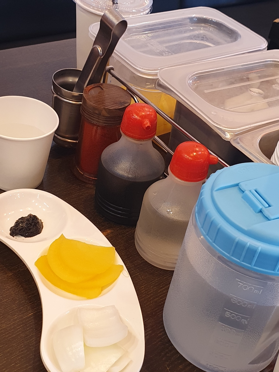 테이블에 준비된 반찬과 소스. 기본적인 밑반찬과 음료가 제공됩니다