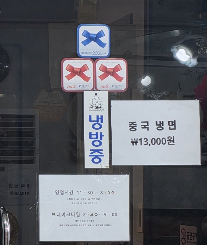 출입문에 붙은 블루리본서베이 2025 선정 스티커와 영업시간 안내문.