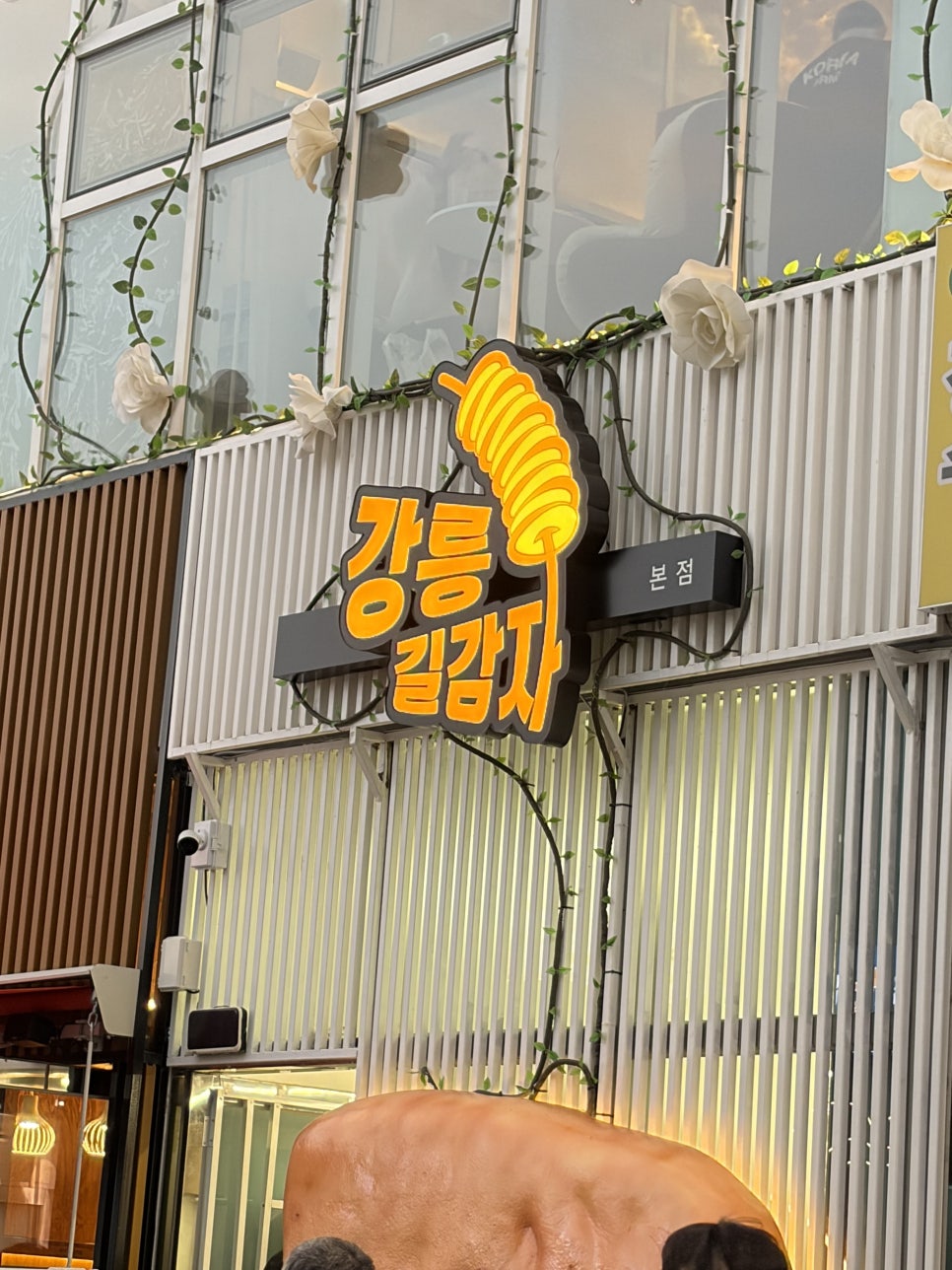 강릉길감자 본점 외관과 간판. 감자 모양의 네온사인이 눈에 띕니다.