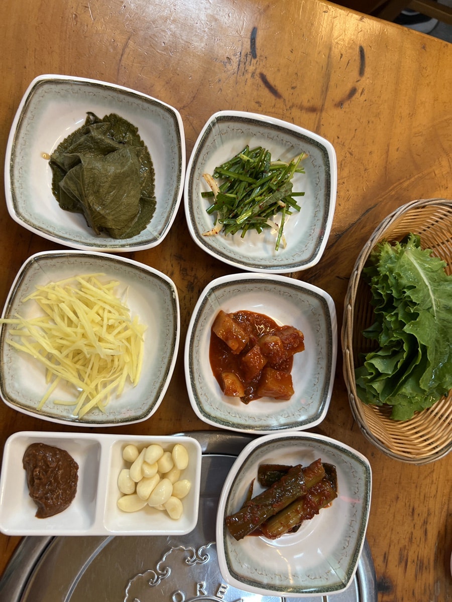 기본으로 나오는 밑반찬 상. 깻잎장아찌·부추무침·마늘과 쌈장·상추까지 정갈하게 담겨 나옵니다.