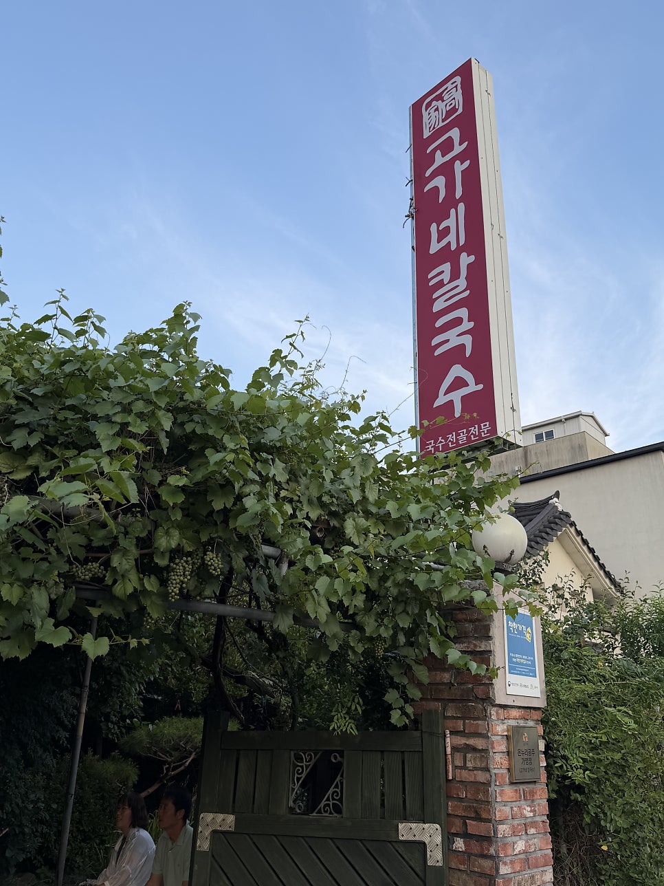 포도 넝쿨이 우거진 대문과 세로형 간판. '국수전골전문'이라는 문구가 눈에 띕니다.