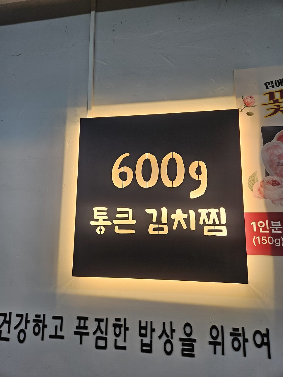 '600g 통큰김치찜' 벽면 조명 간판. 고기와 김치를 한입 크기로 조리해 낸다는 설명이 함께 붙어 있습니다.