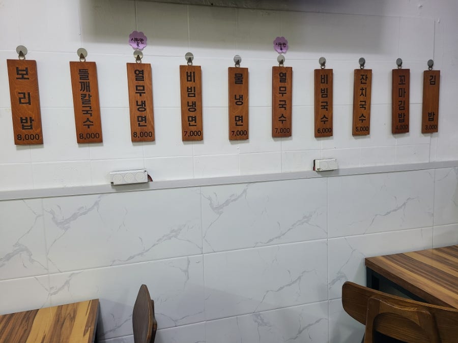 매장 벽에 걸린 메뉴판. 잔치국수 5,000원부터 들깨칼국수·보리밥 8,000원까지 국수·냉면류가 다양합니다.