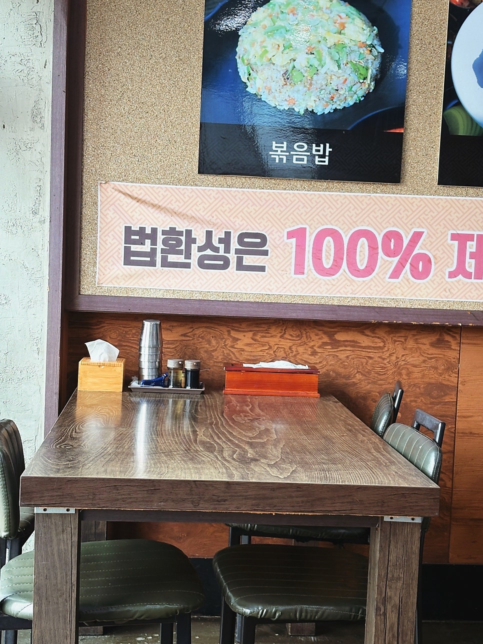 가게 내부의 테이블과 메뉴판. "법환성은 100% 돼지..."라는 안내문이 붙어 있습니다.