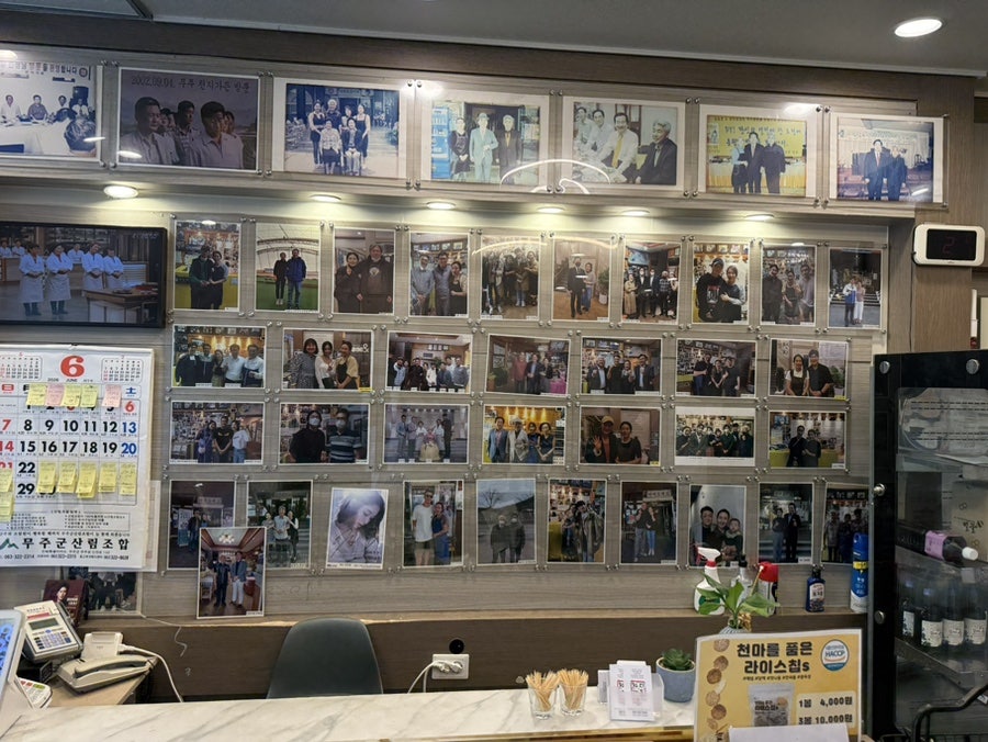 카운터 뒤편을 가득 채운 방문객 사진과 사인들. 달력에는 예약이 빼곡하고, 천마 라이스칩(1봉 4,000원·3봉 10,000원)도 함께 팔고 있습니다.