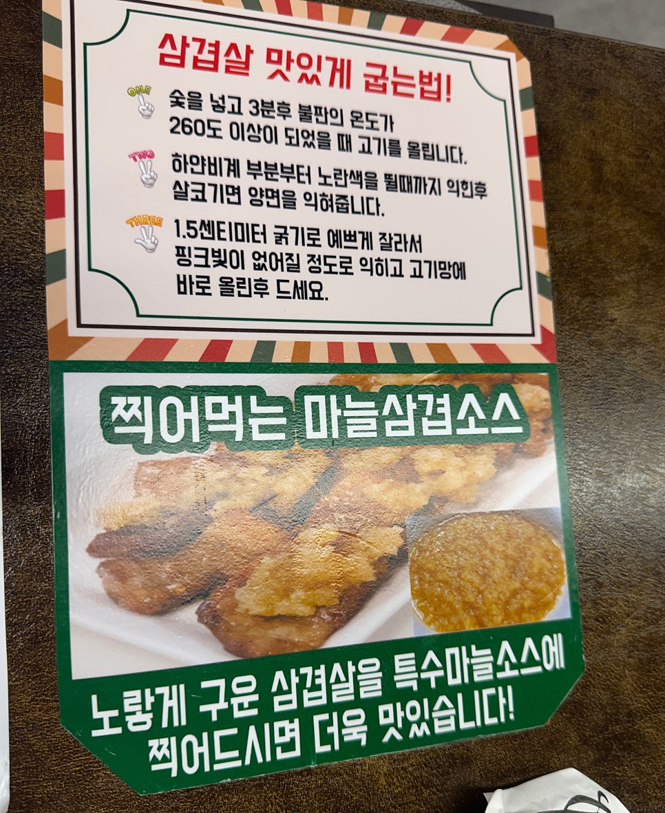 매장 테이블에 붙어 있는 삼겹살 굽는 법과 마늘삼겹소스 안내. 불판 온도 260도, 1.5cm 두께로 구우라는 팁이 적혀 있습니다.