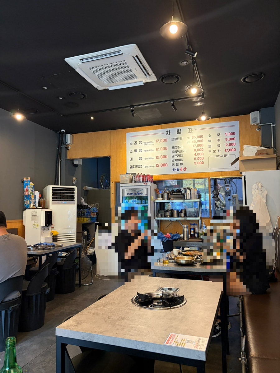 테이블마다 놓인 개별 화구와 벽면의 차림표. 아늑한 조명의 실내입니다.